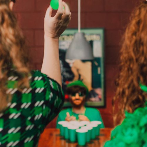 Group of adults playing games at a lively St. Patrick's Day party in festive attire.