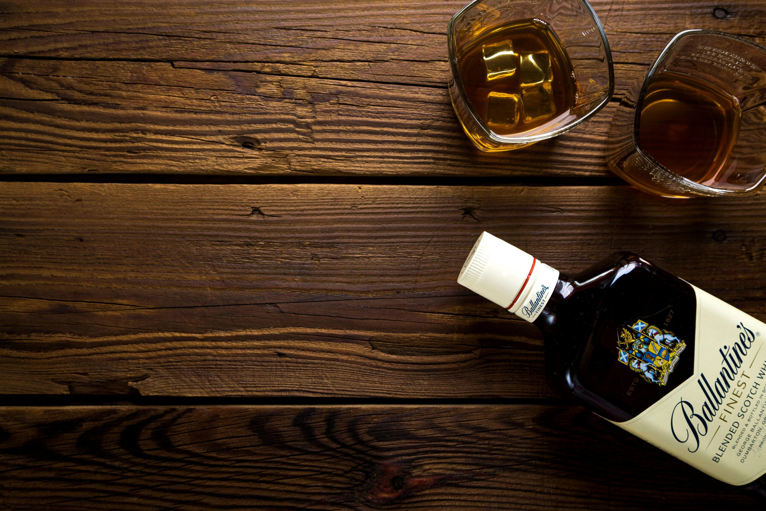 Top view of whiskey bottle and glasses on rustic wooden table, ideal for bar or celebration themes.